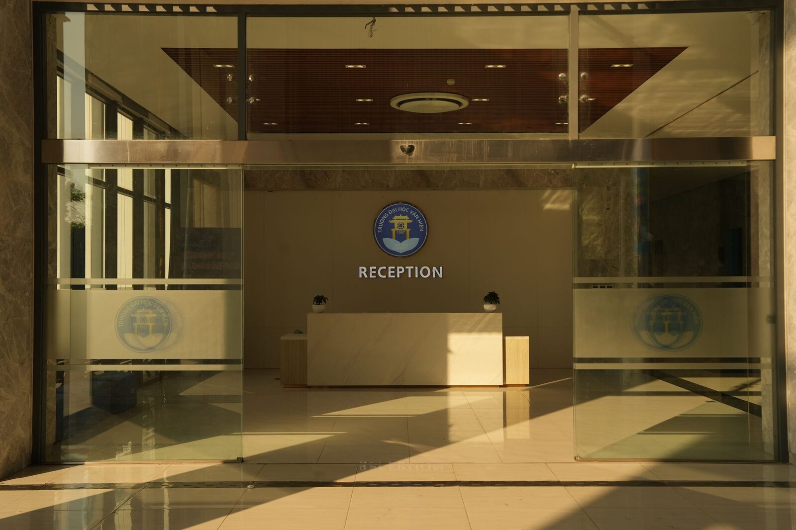 Spacious office reception area with logo on wall and natural lighting.